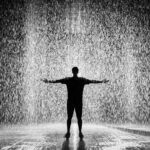 silhouette and grayscale photography of man standing under the rain
