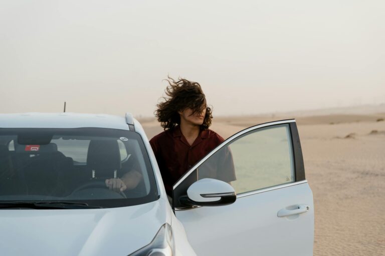 man in the desert holding the steering wheel of a white car