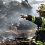 fire fighter wearing black and yellow uniform pointing for something