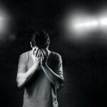 monochrome photo of man covering his face