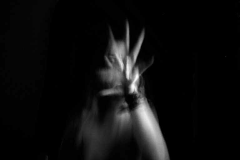 blurred motion of woman with her hand up and reaching towards the camera