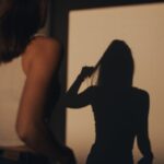 woman looking at her shadow while holding her hair