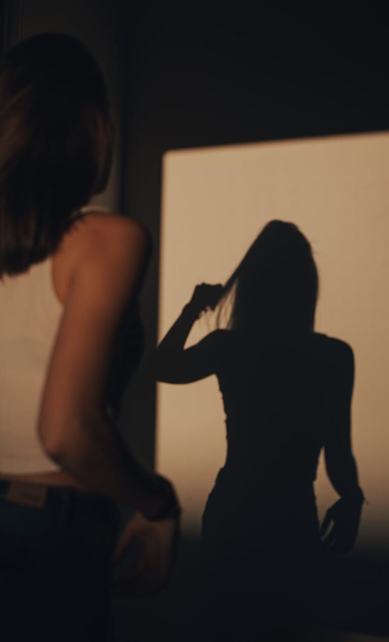 woman looking at her shadow while holding her hair
