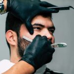 person shaving a man s face with straight razor