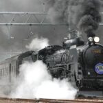 black train on rail and showing smoke