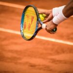 close up photo of person holding tennis racket and ball