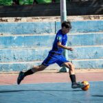 teenage boy playing soccer on outdoor court