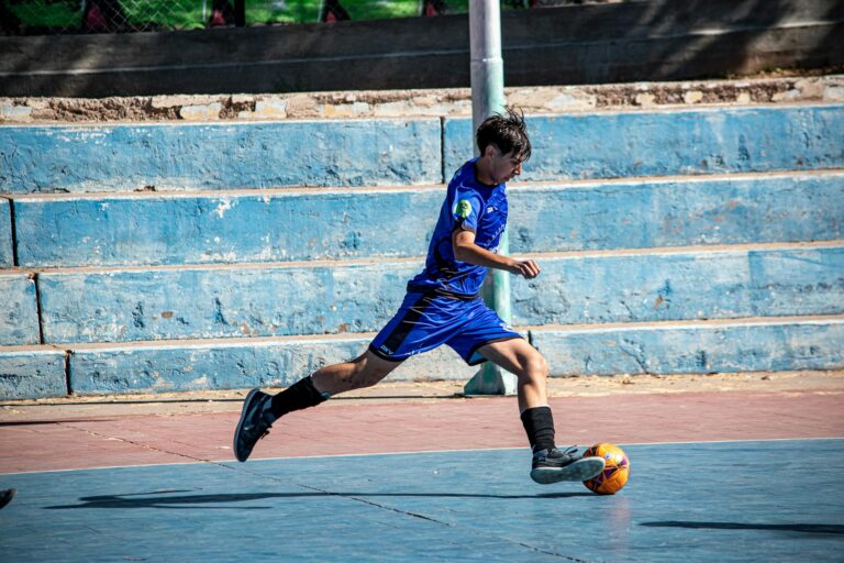 teenage boy playing soccer on outdoor court