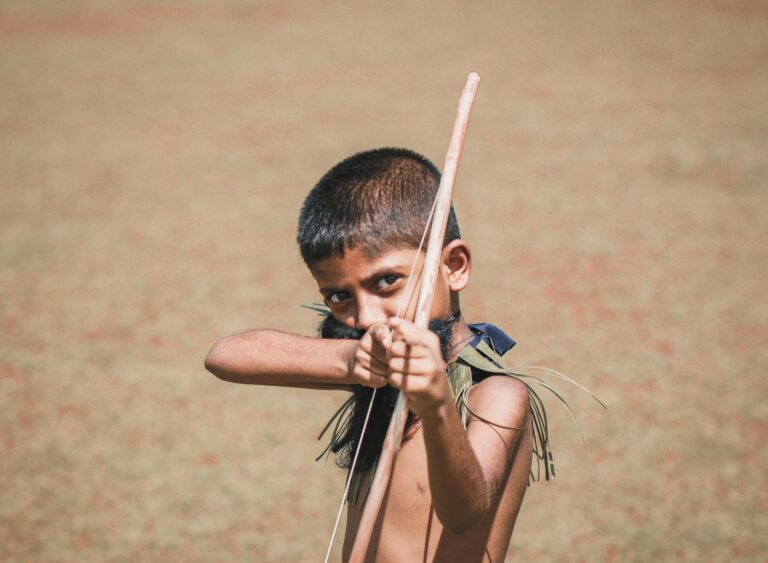 young boy playing with bow and arrow outdoors