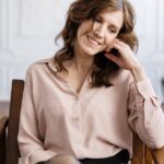 woman in white dress shirt sitting on brown wooden chair