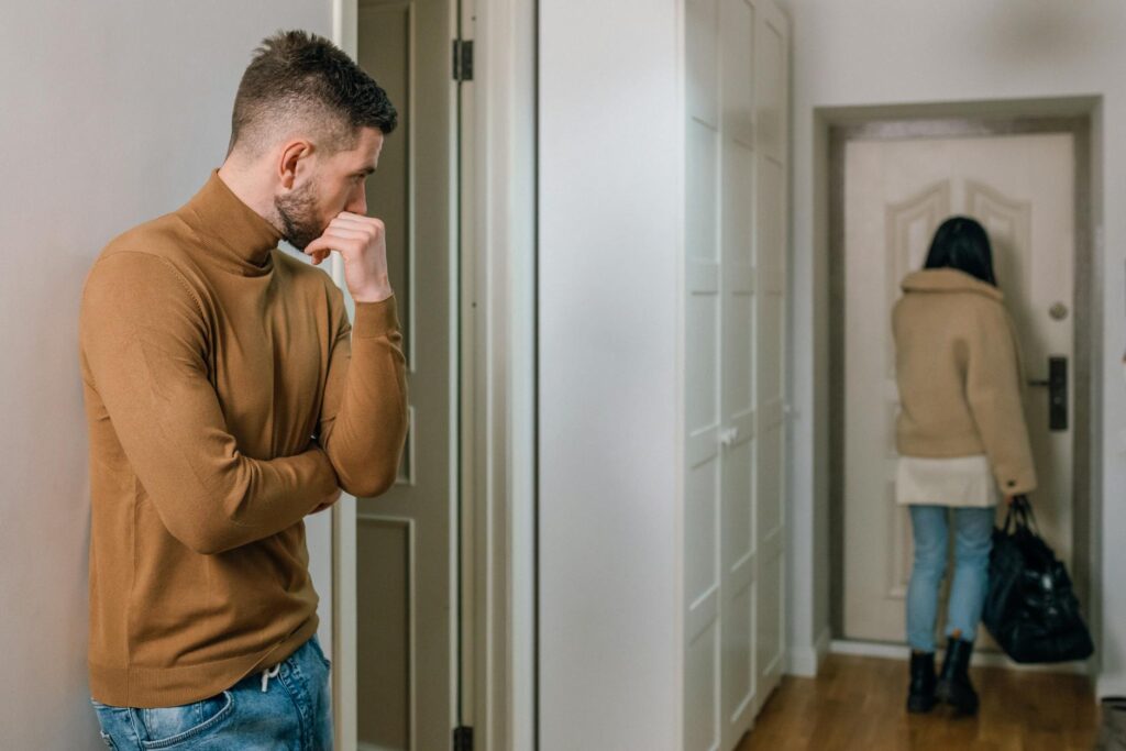 man looking at a woman walking out of the apartment