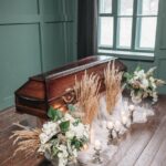 a brown wooden coffin decorated with white flowers on the floor