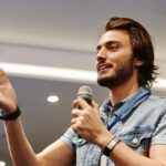 man in blue denim vest holding microphone