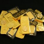 gold bars and coins on a black surface